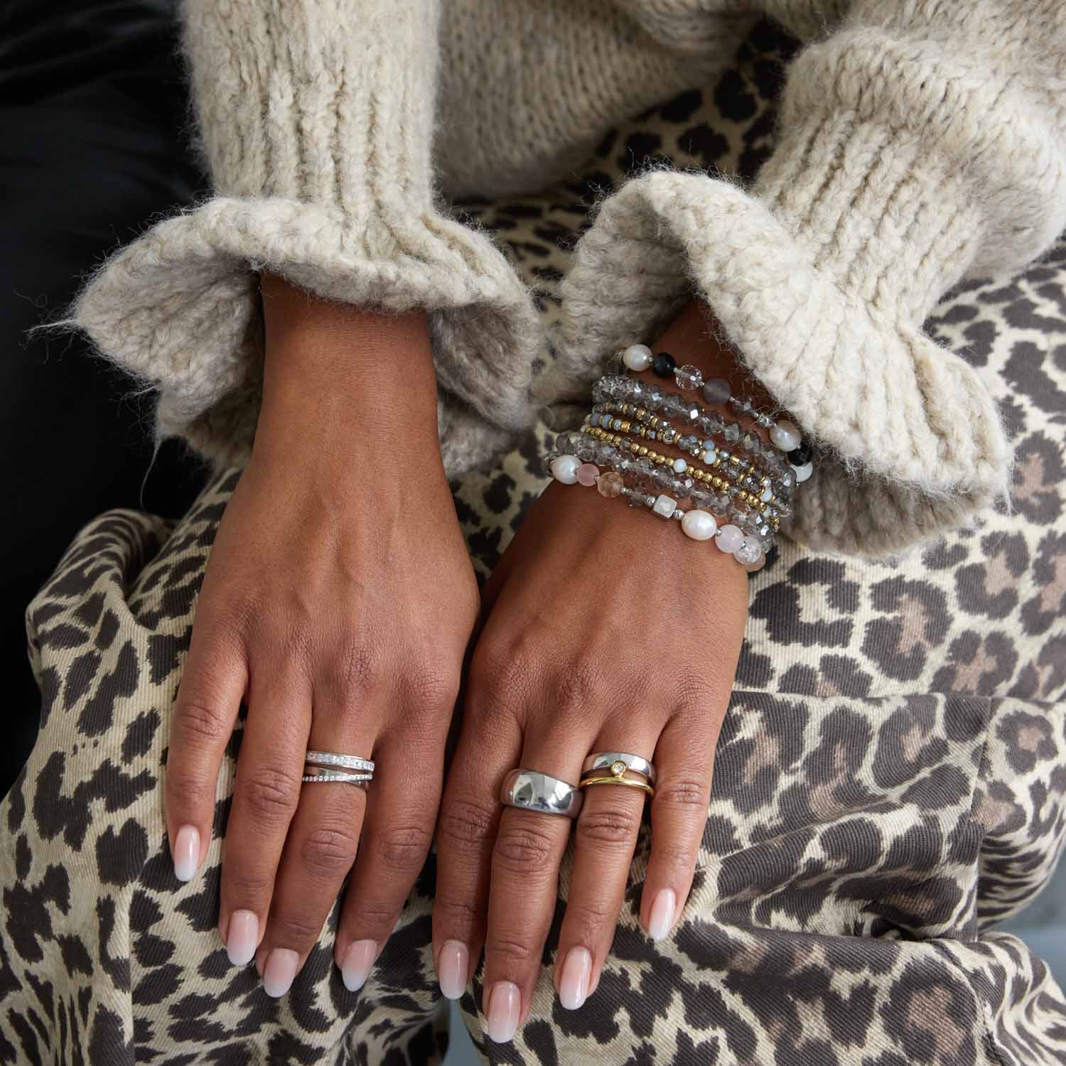 Haende einer Frau mit Ring CLAIRE 20, Beaded-Armbändern und Leoparden-Muster-Stoff