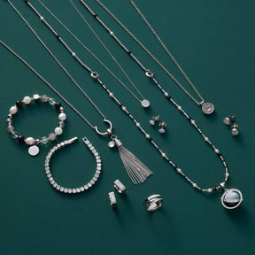 Silberner Schmuck der Serie SARAH auf grünem Hintergrund: Ketten, Armbänder, Ohrringe und Ring