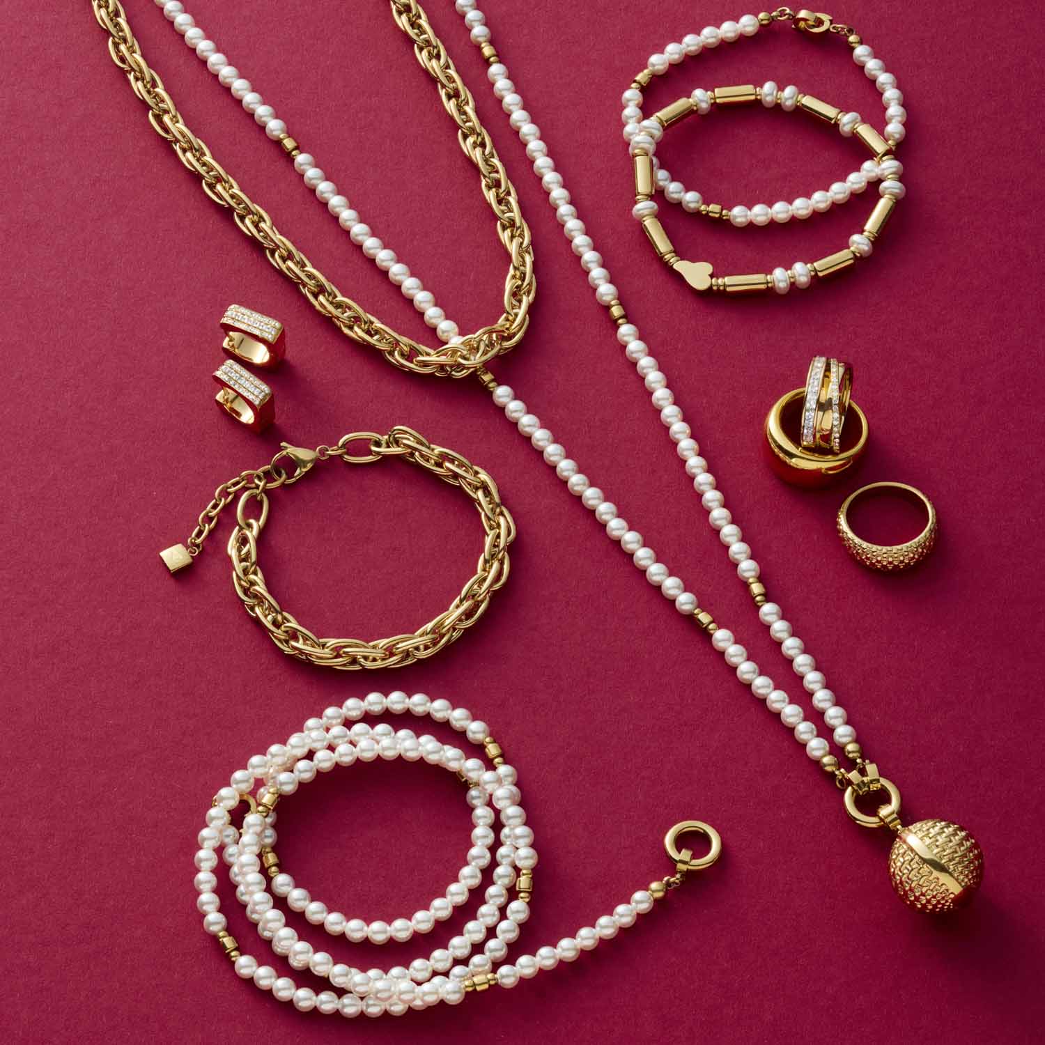 Schmuckkollektion mit goldenen Ketten, Perlenarmbaendern, Ringen und Ohrringen auf pink-rotem Hintergrund