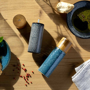 Gewürzmühle MATERA in Blau mit Holzgriff und Keramikmahlwerk auf Holztisch mit Dekoelementen