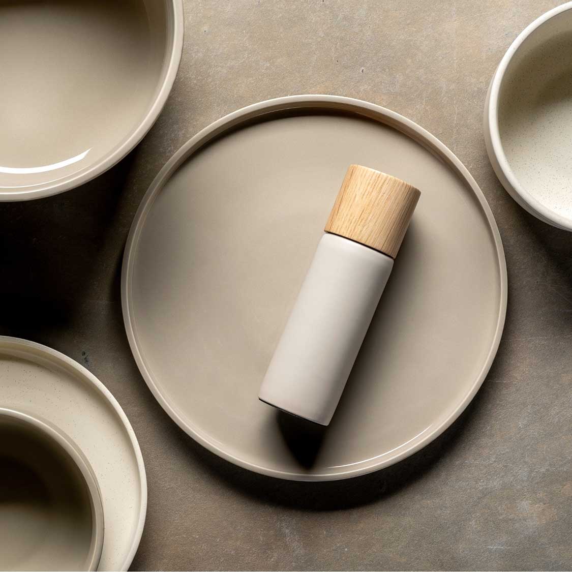 Gewürzmühle ROMA in beige mit Holzkappe auf rundem Tablett, umgeben von leeren Schalen