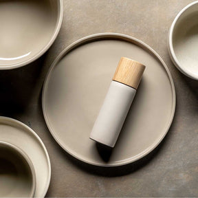 Gewürzmühle ROMA in beige mit Holzkappe auf rundem Tablett, umgeben von leeren Schalen