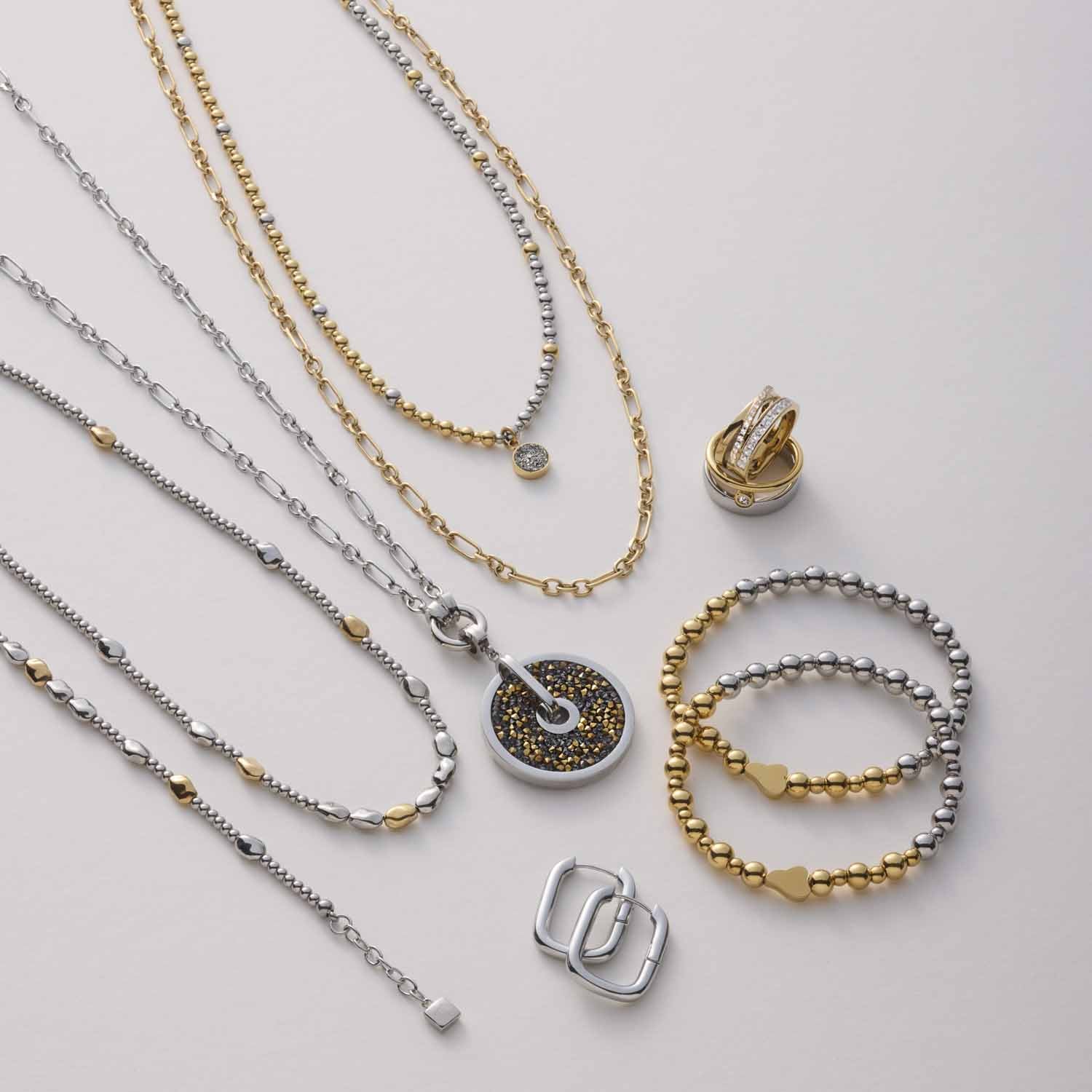 Schmuckkollektion mit Ketten, Ringen und Armbändern in Silber und Gold auf weißem Hintergrund