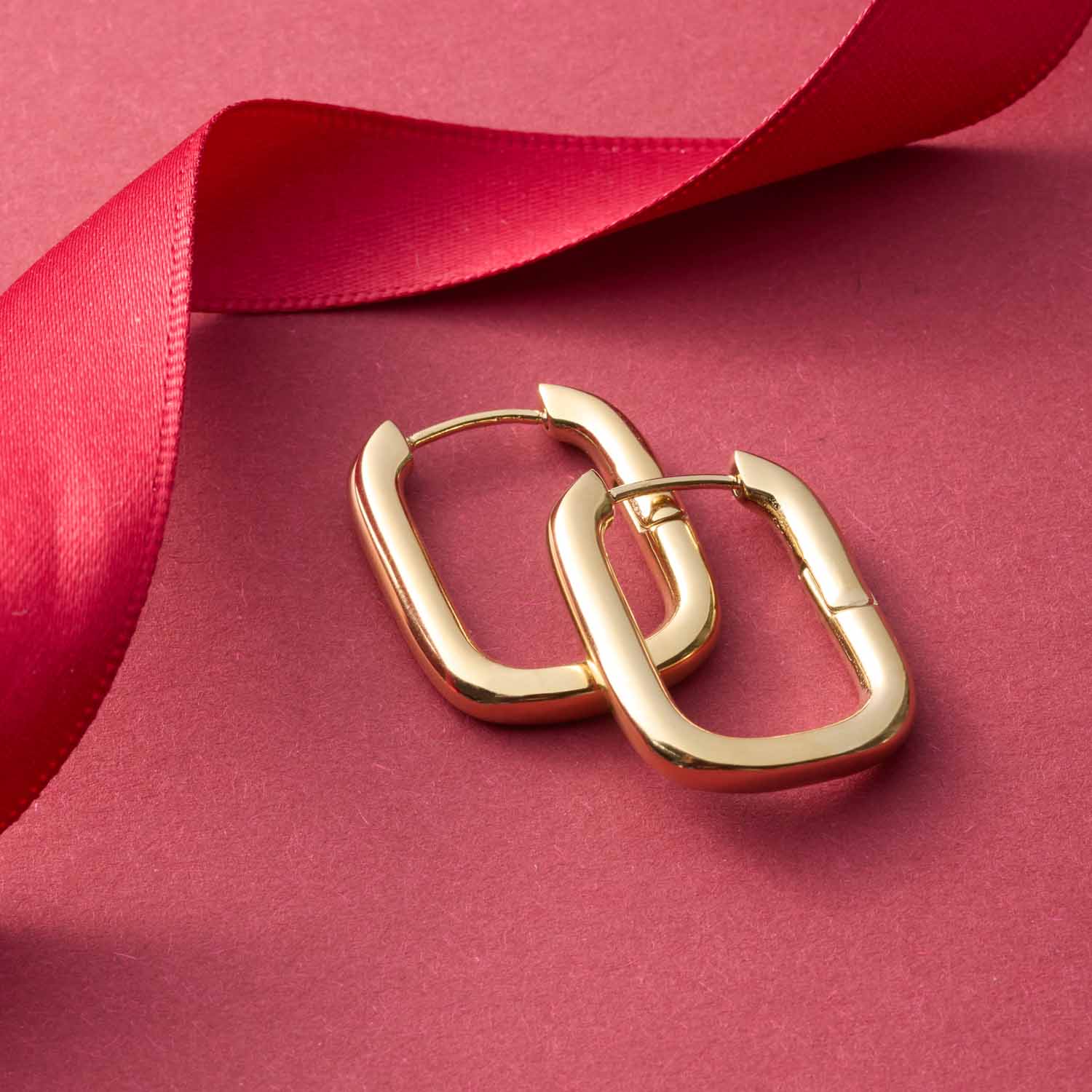 Creole BERNICE gold auf rosa Hintergrund mit rotem Seidenband