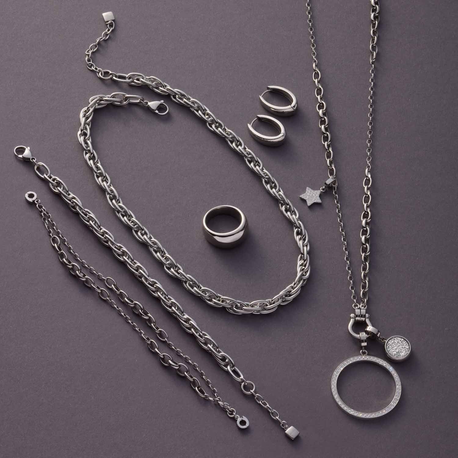 Creole ELODIE Serie in Silber, Kettenanhänger und Ringe auf grauem Hintergrund