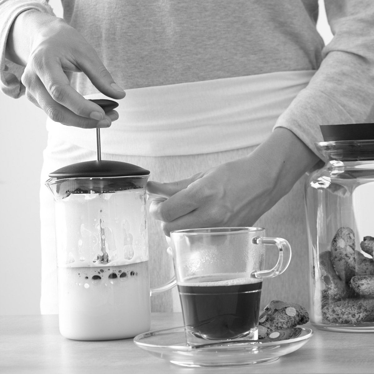 Frau nutzt Milchaufschäumer CAFFEE PER ME in Küche mit Tasse und Gläsern