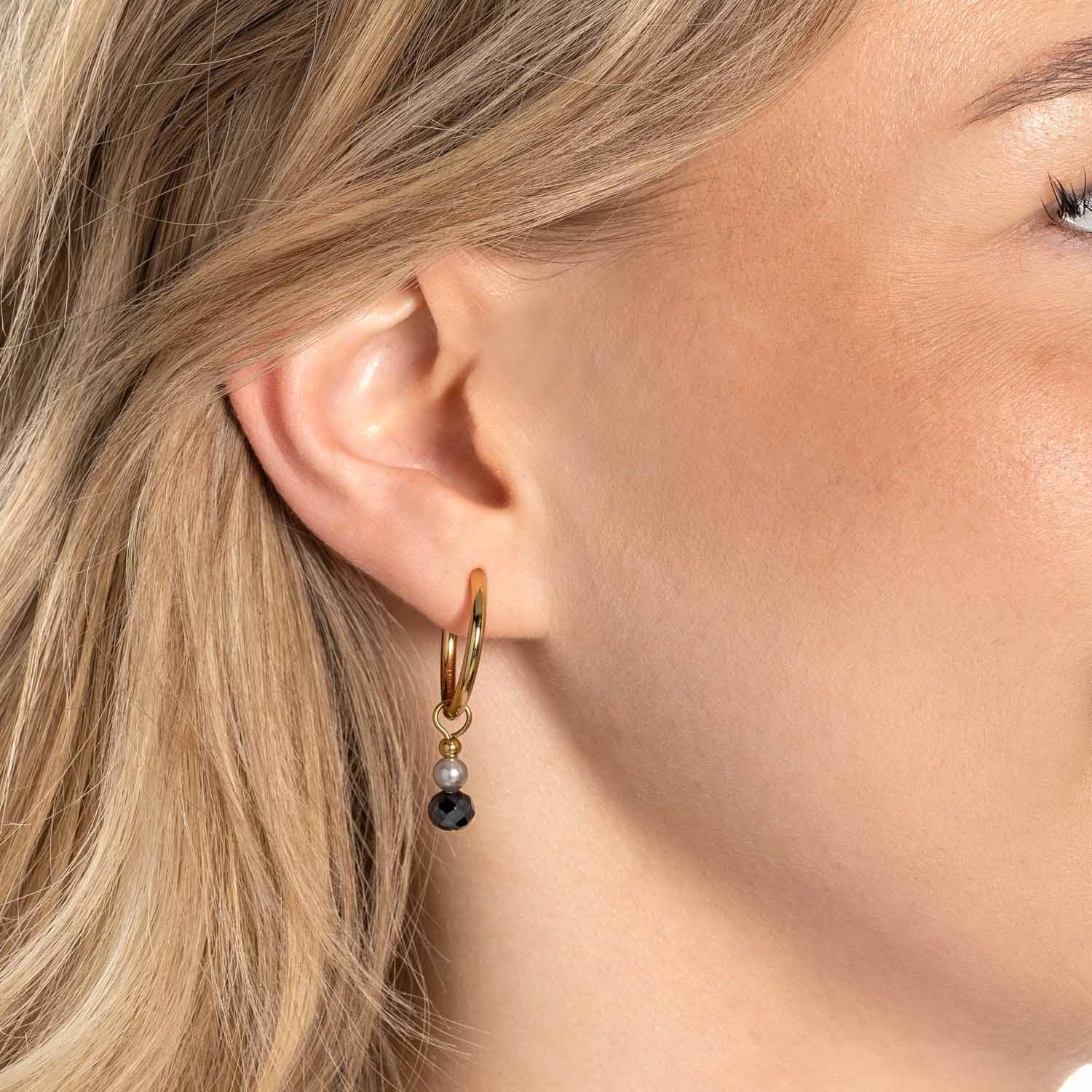 Frau trägt goldene Ohrringe ALINE mit schwarzem Glasanhänger