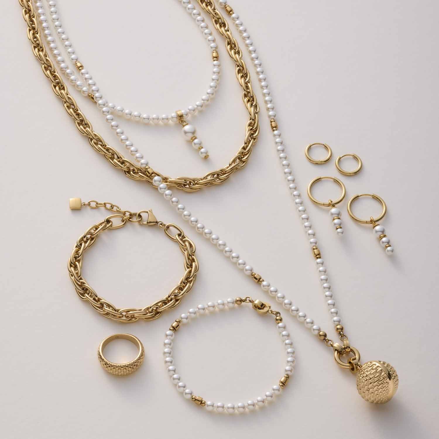 Goldene Ketten, Perlenarmbänder und Ringe in Flatlay-Anordnung auf hellem Untergrund