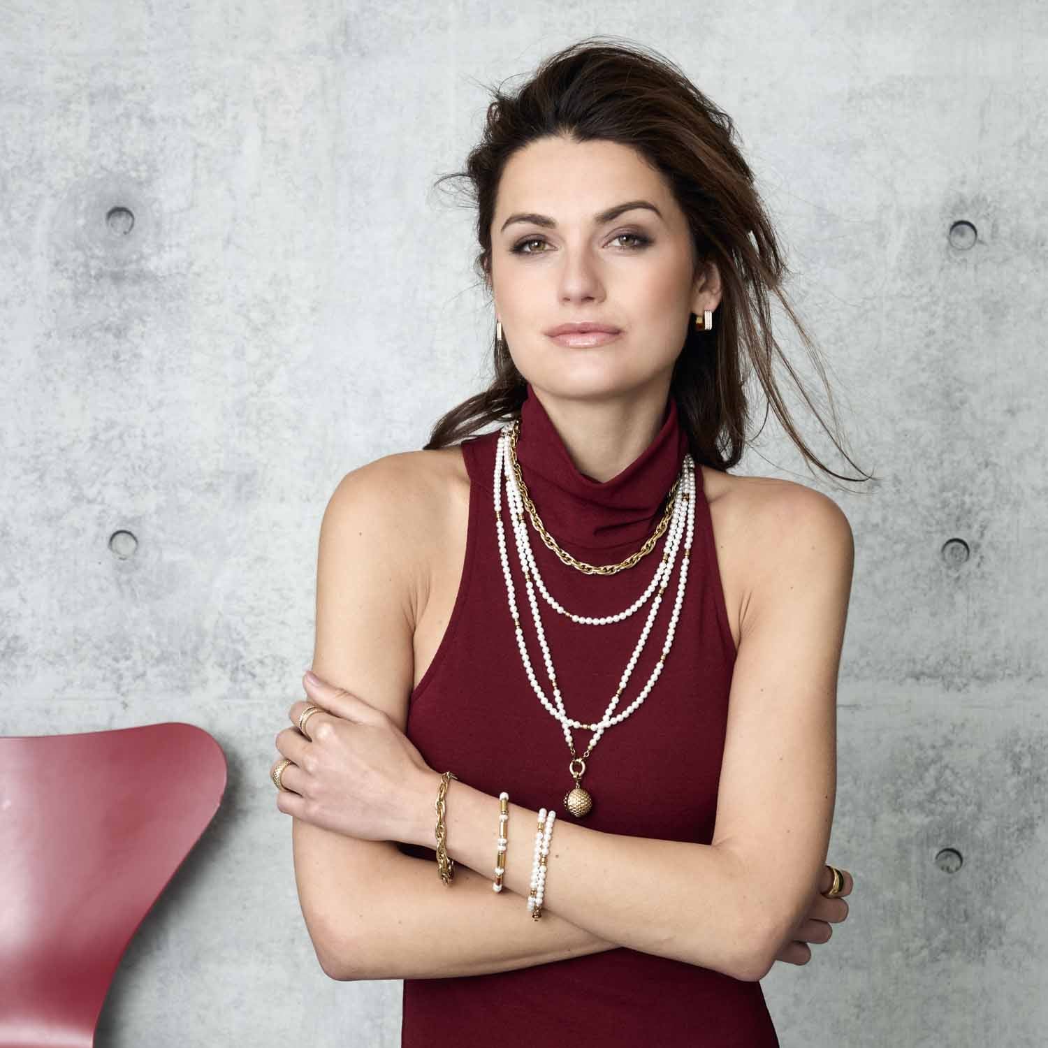 Frau trägt Armband CHRISTA Clip & Mix gold am Handgelenk mit Halsketten