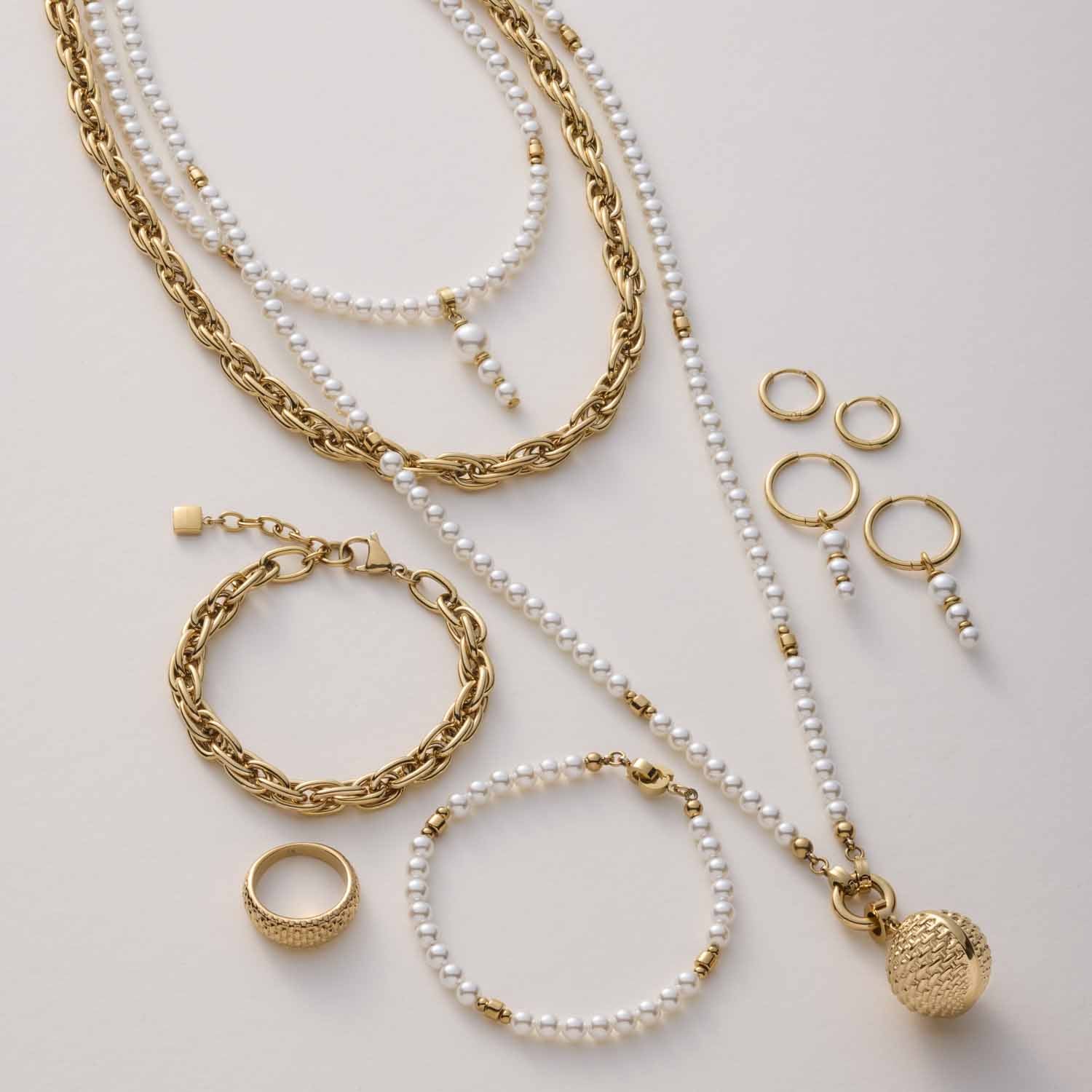 Goldfarbene Ketten, Armbänder und Ringe mit Perlen auf hellem Untergrund