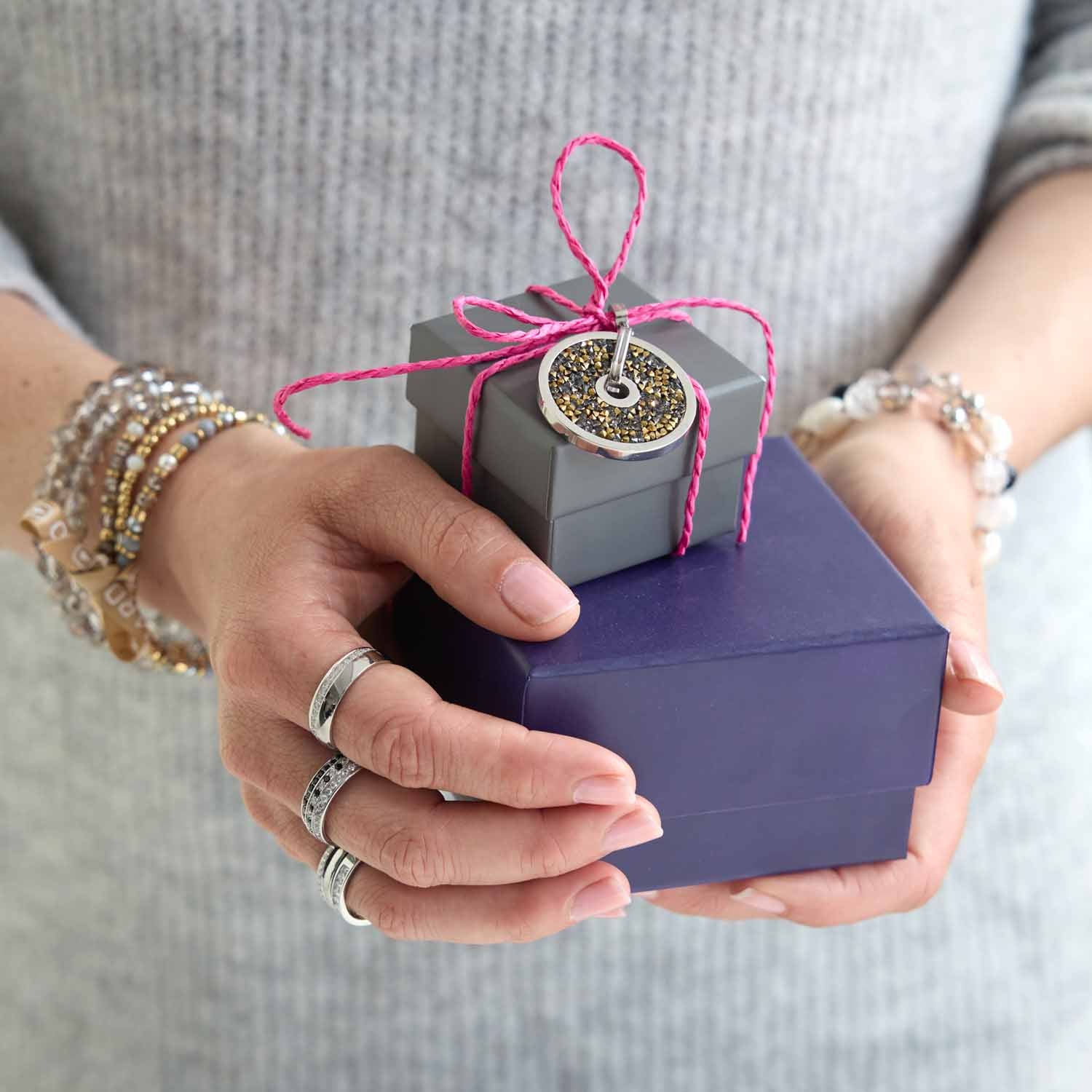 Frau hält verpacktes Geschenk mit Anhänger BLANCA GREY Clip & Mix