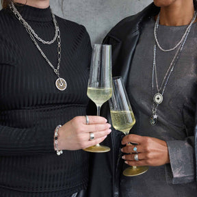 Zwei Personen mit Champagnergläsern und Schmuck tragen Anhänger JAMIRA BLUE Clip & Mix
