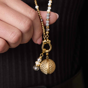 Anhänger PINOU Clip & Mix gold an Perlenkette, in Hand gehalten