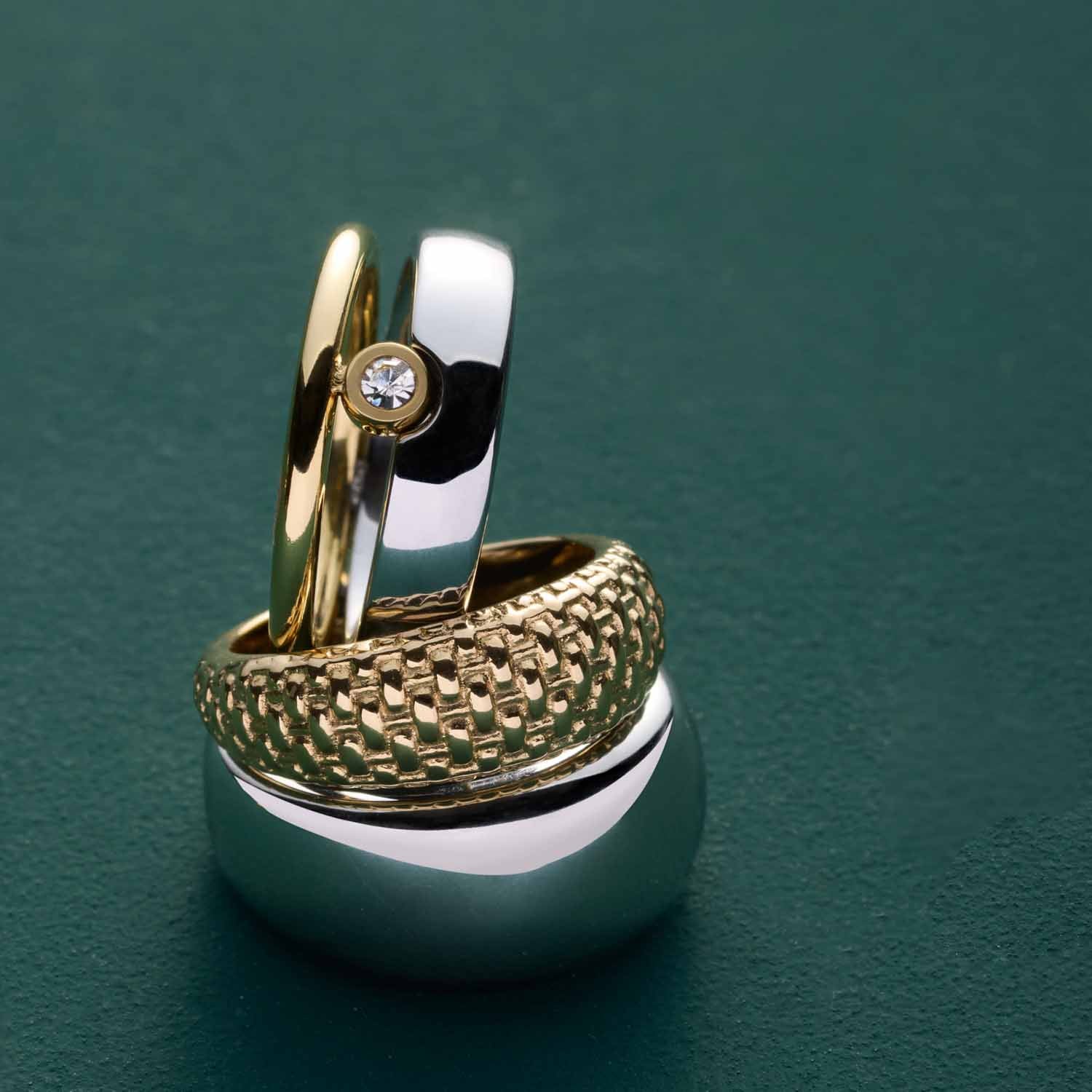 Ring PINOU 17 gold auf grünem Untergrund mit weiteren Ringen