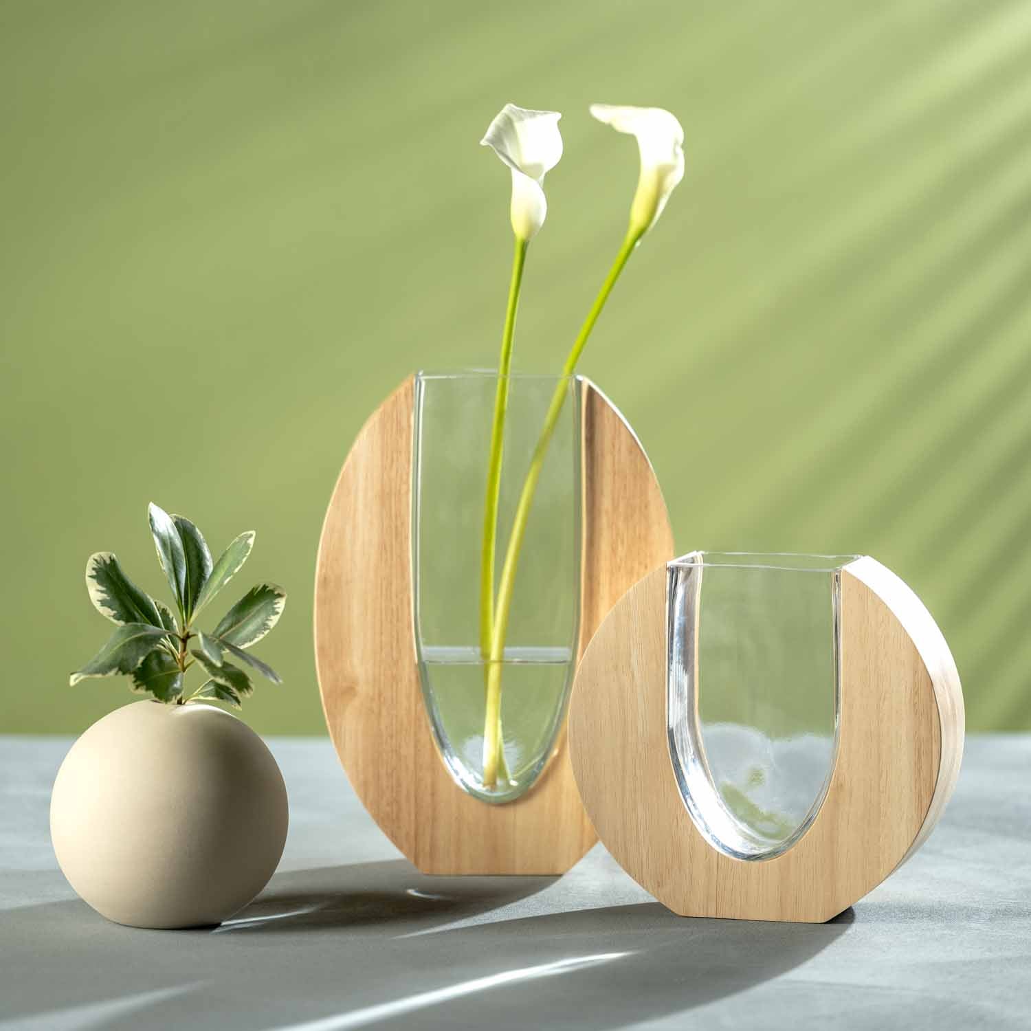 Vase LEGNO mit Holzmantel, gefuellt mit weissen Blumen und Gruen, neben Keramiktoepfchen auf Tisch