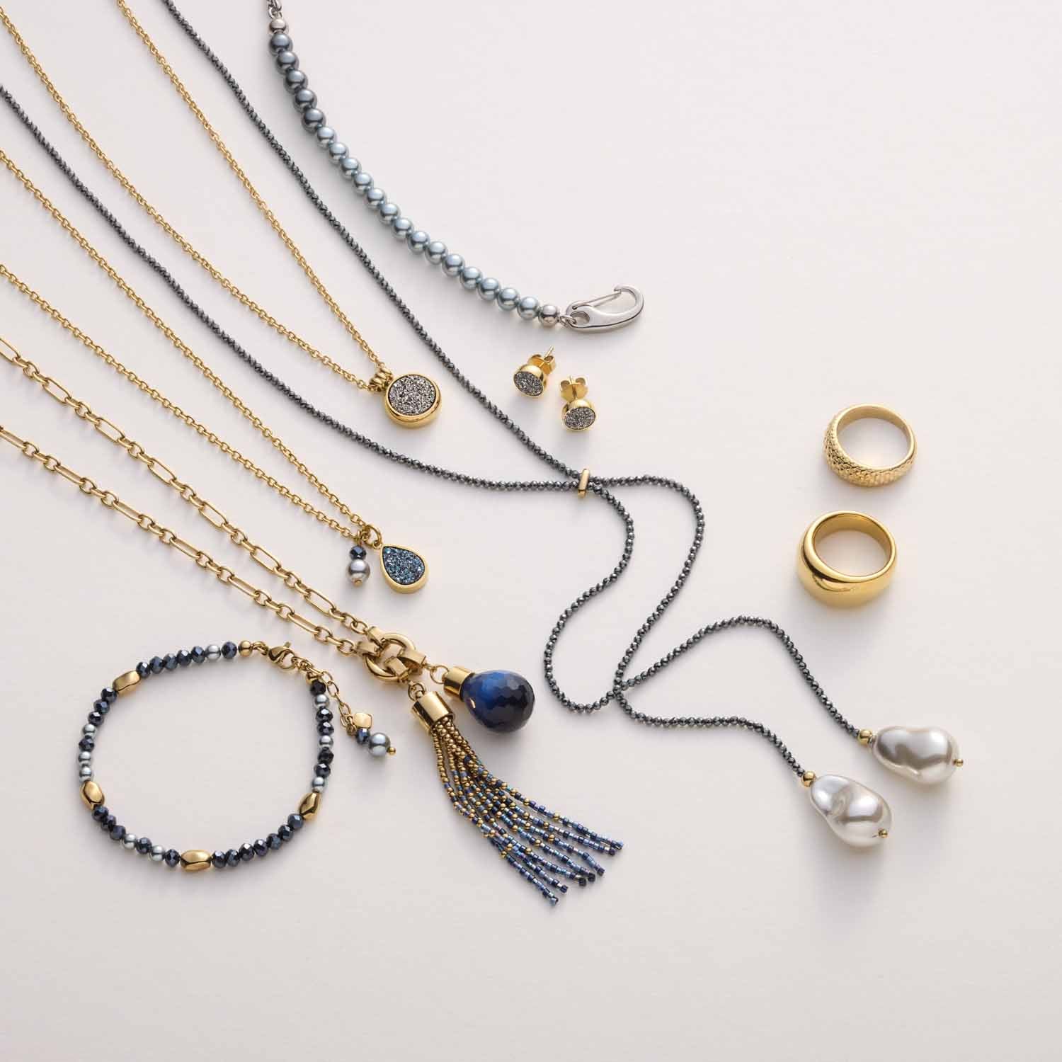 Schmuckkollektion mit Anhängern, Ketten, Ringen und Armbändern in Gold und Grau auf weißem Hintergrund