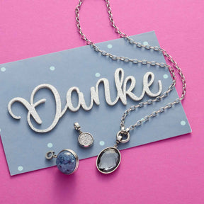 Anhänger SNOWBALL BLUE Clip & Mix mit Silberkette auf Dankeskarte vor rosa Hintergrund