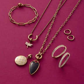 Goldener Schmuck auf rosa Untergrund: Armband, Ketten, Anhänger und Ringe