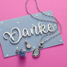 Anhänger MAURINE Clip & Mix an Kette auf blauer Karte mit "Danke"-Schriftzug