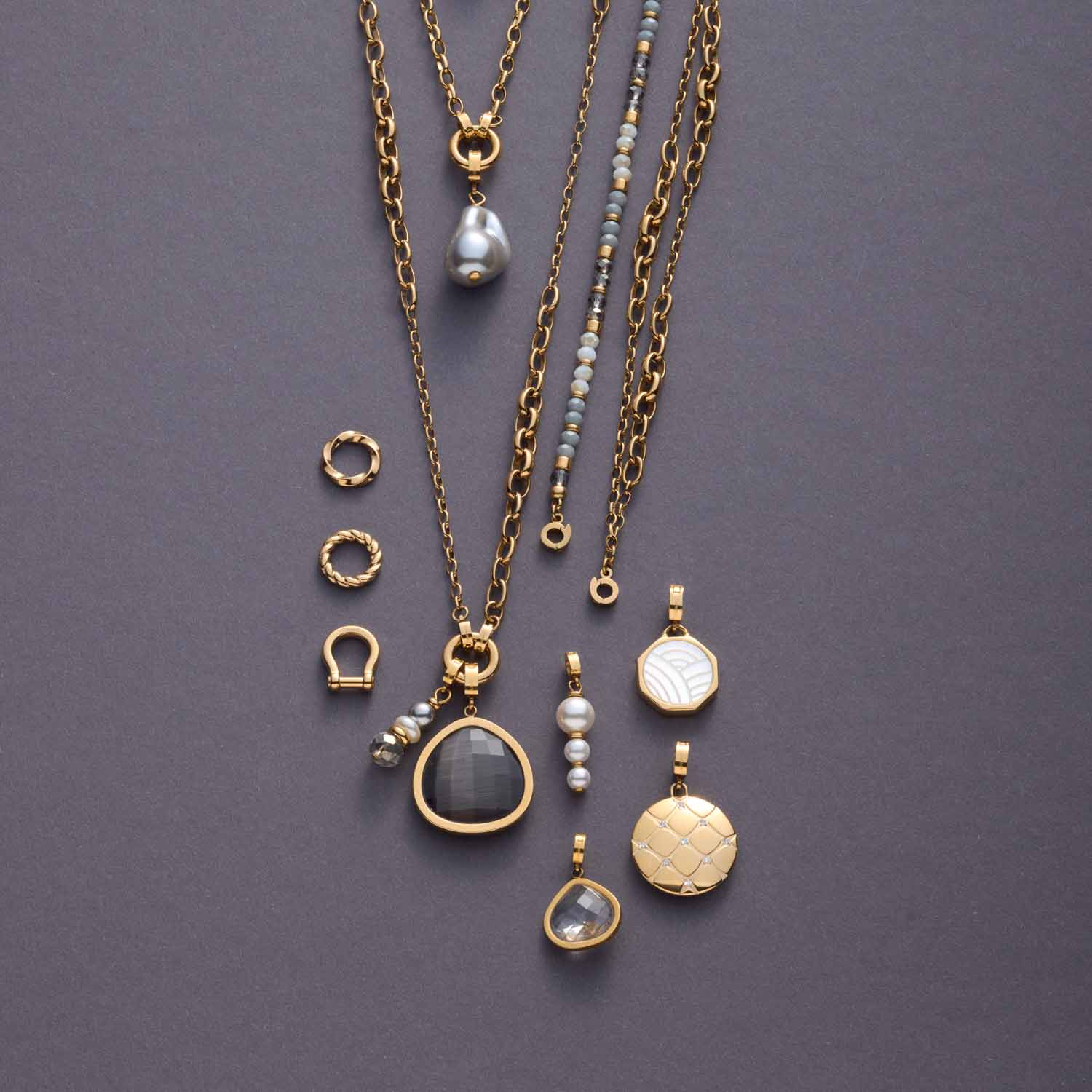 Anhänger JUVINGA WHITE Clip & Mix gold mit verschiedenen Glas- und Perlenanhängern auf grauem Untergrund