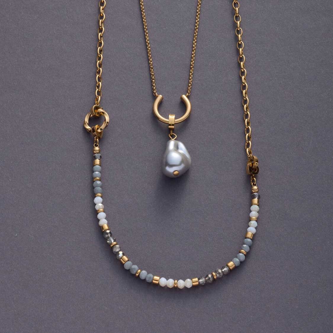 Drei goldene Halsketten mit Perlen und Edelstahlring auf grauem Hintergrund