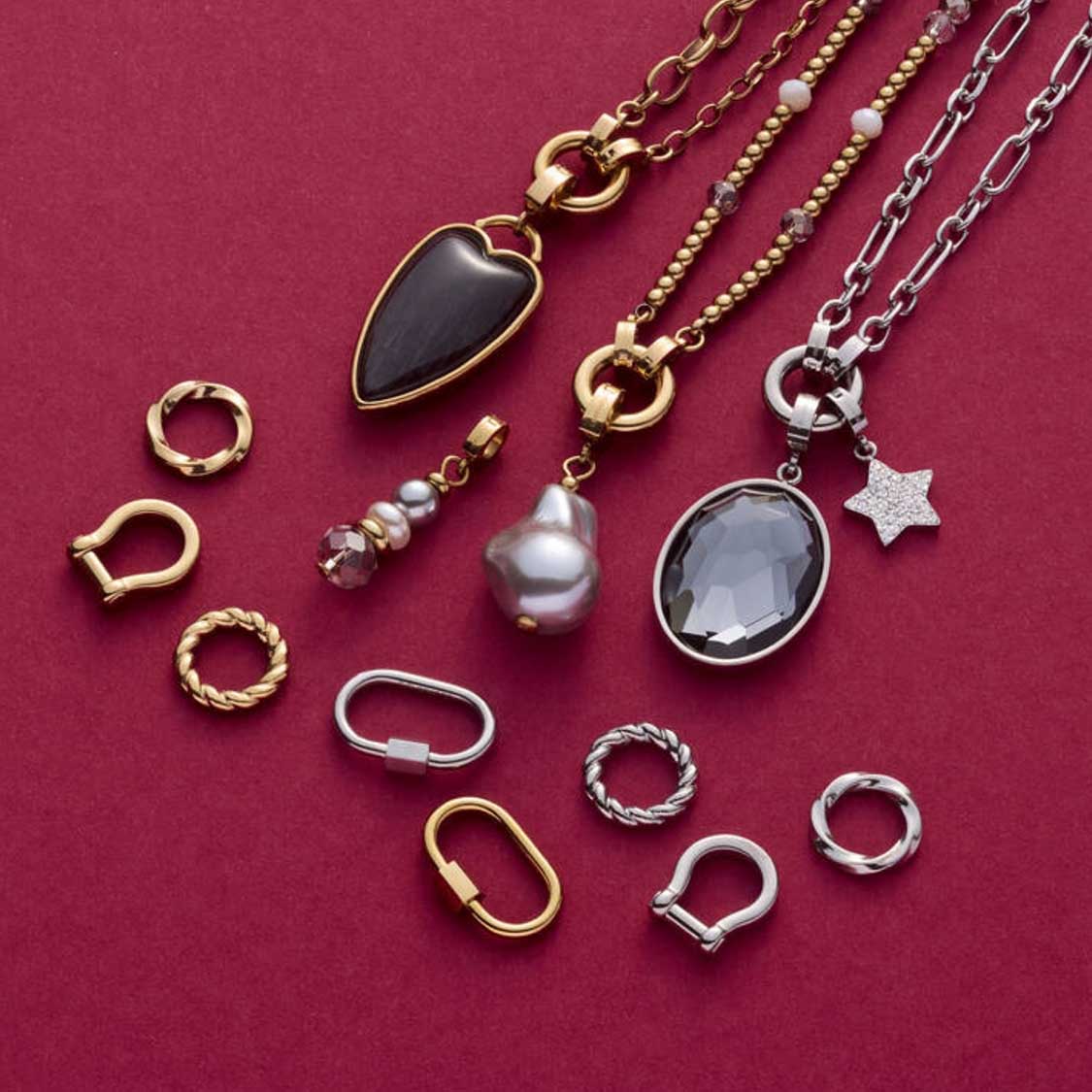 Schmuckkollektion mit Edelstahlringen, Ketten und Anhängern in Gold und Silber auf magentafarbenem Untergrund