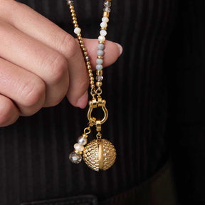 Hand hält goldenen Schäkel LENI Clip & Mix mit Perlenanhänger