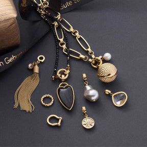 Schäkel LENI Clip & Mix gold mit verschiedenen Charms und Anhängern auf grauem Untergrund