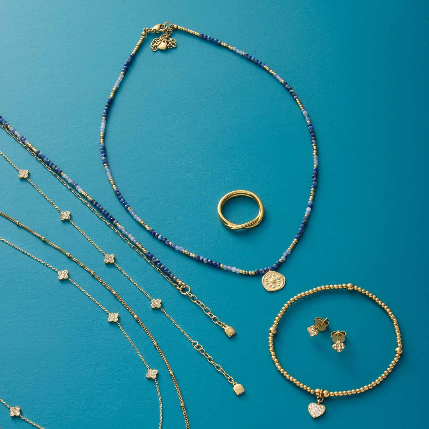 Schmuckkollektion mit Halskette ROSE, Ringen, Armbändern und Ohrringen auf blauem Hintergrund