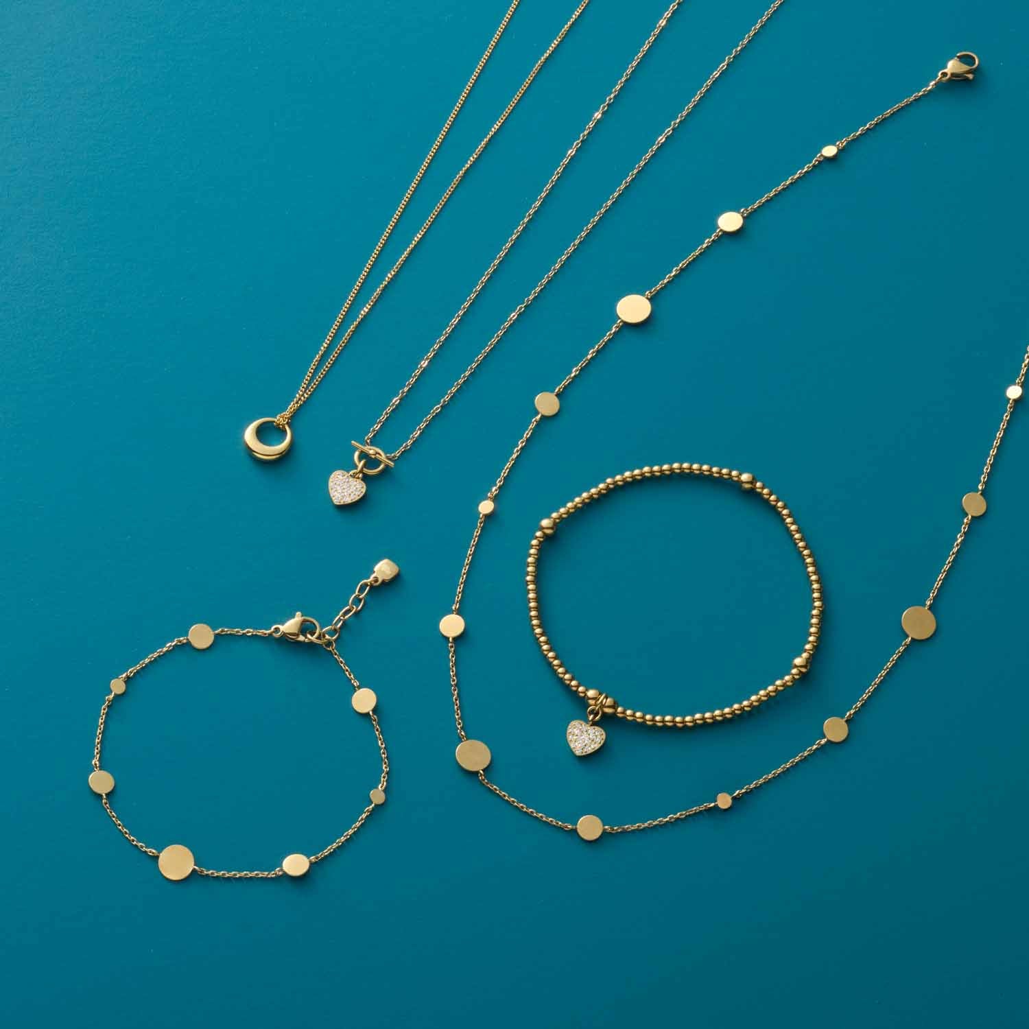 Goldene Schmuckstücke und Armbänder auf türkisblauem Hintergrund arrangiert