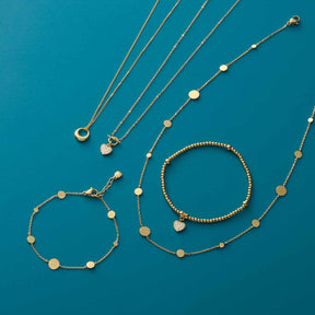 Goldene Schmuckstücke und Armbänder auf türkisblauem Hintergrund arrangiert