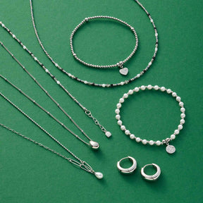Schmuckkollektion aus Halsketten, Armbändern und Ringen auf grünem Hintergrund