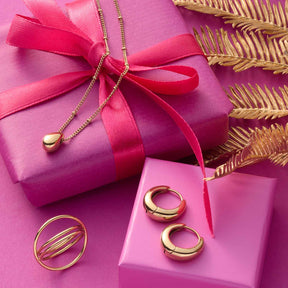 Creole CLOTHILDE gold mit Schmuckstücken auf rosa Geschenkbox und Dekoration