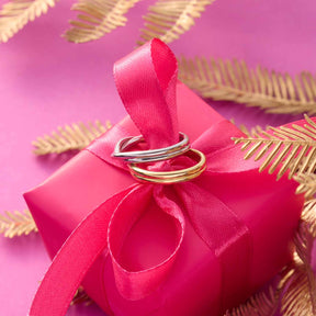 Ring TWISTER 17 gold auf rosa Geschenkbox mit Schleife und goldenen Blättern