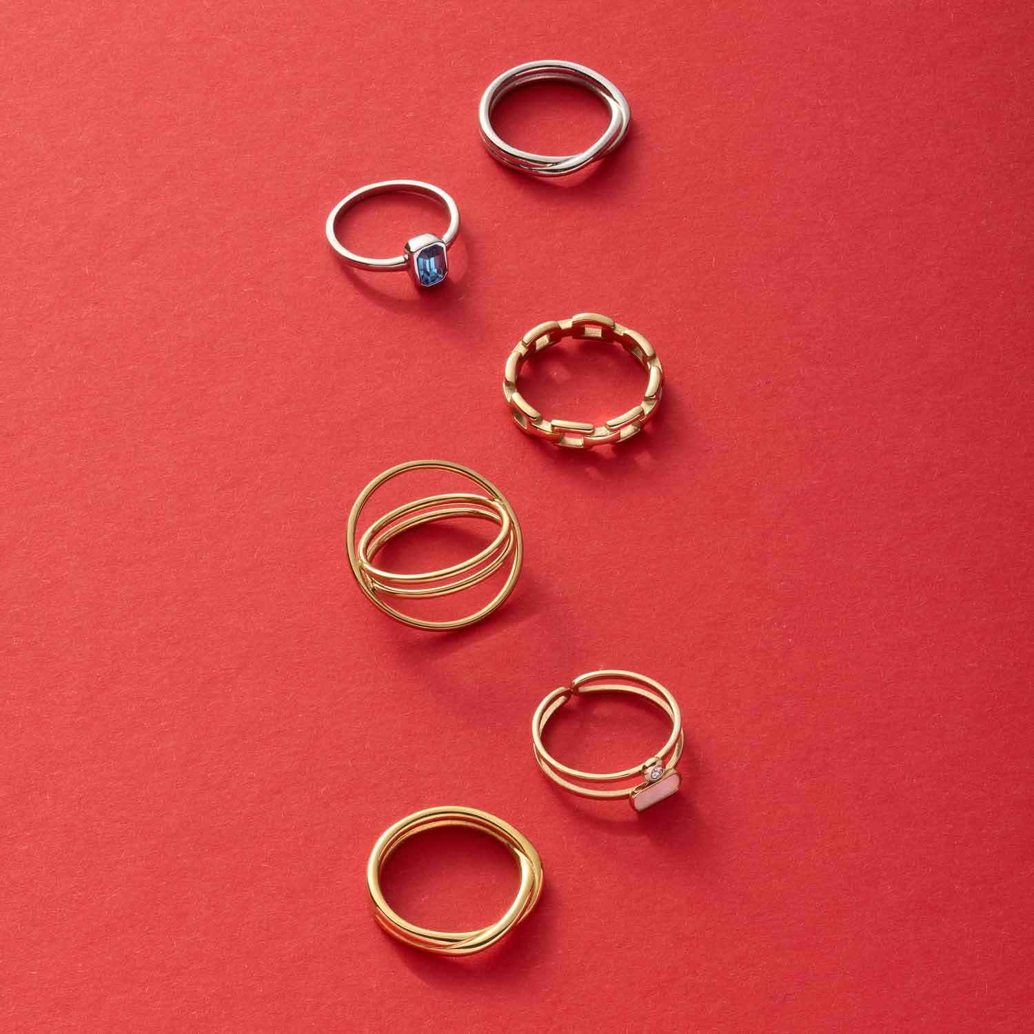 Sechs goldene und silberne Ringe auf rotem Hintergrund arrangiert