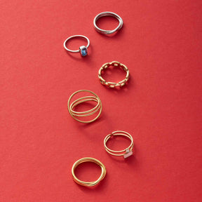 Sechs goldene und silberne Ringe auf rotem Hintergrund arrangiert