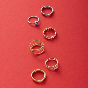 Sechs goldene und silberne Ringe auf rotem Hintergrund arrangiert
