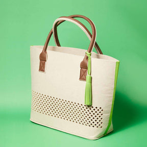 LEONARDO Beach Bag grün mit Lochornament, braune Henkel und grüne Quaste vor grünem Hintergrund
