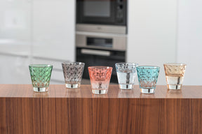 Sechs Trinkgläser OPTIC in Pastellfarben auf Holzoberfläche, Küchenzeile im Hintergrund