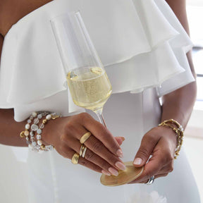 Frau in weißem Kleid mit Armband HOPE silber/rose und Champagnerglas