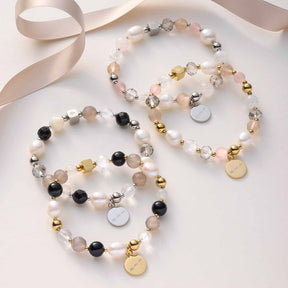 Drei Armbänder HOPE gold/rose mit Perlen und Metallplaketten auf weißem Untergrund