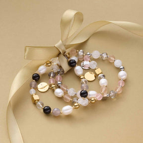Armband HOPE gold/rose mit Perlen und Schleife auf beigem Untergrund