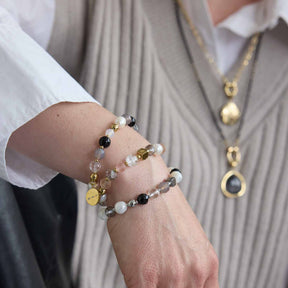 Frau trägt mehrere Armbänder mit Perlen und Metallplättchen am Handgelenk
