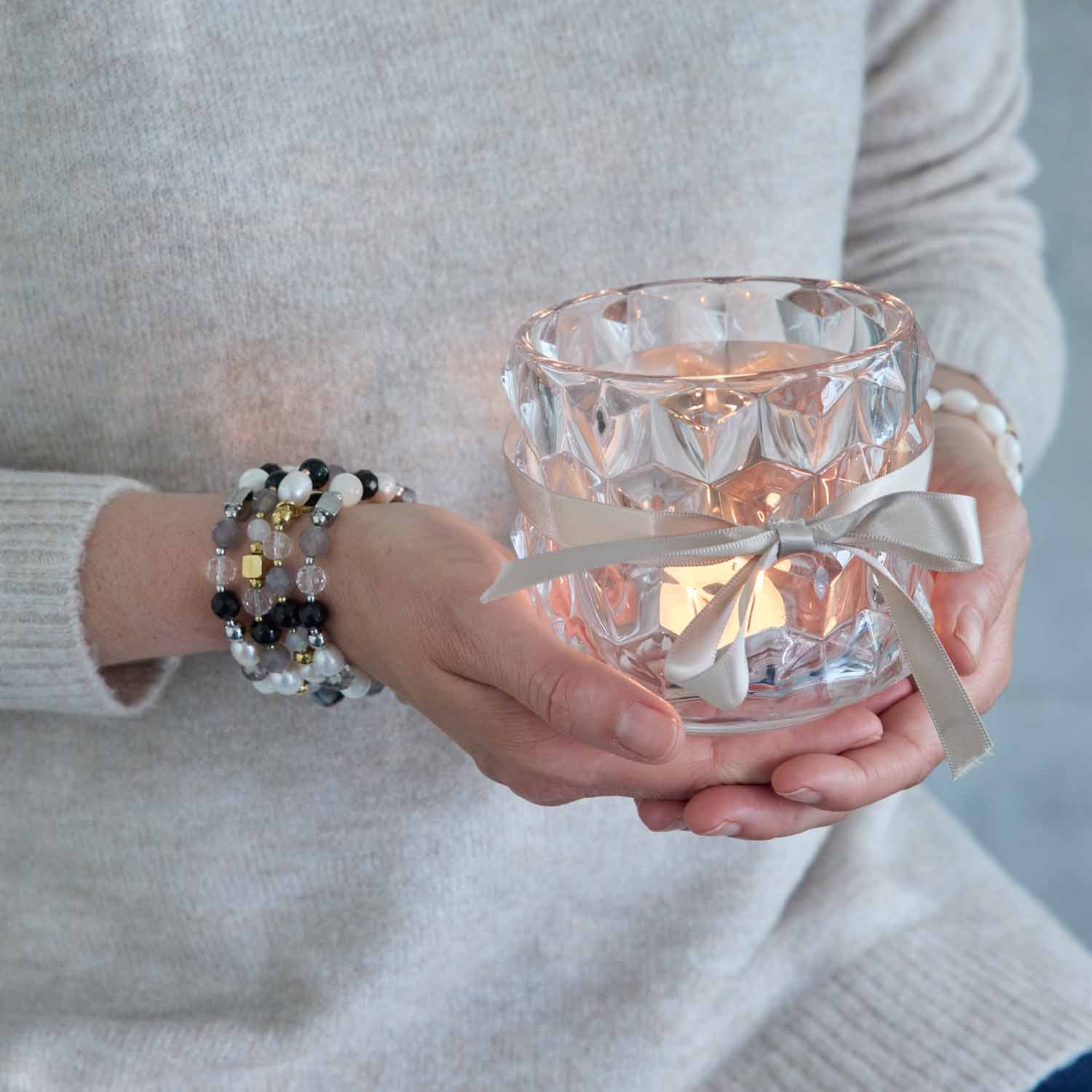 Frau trägt Armband HOPE silber/grau mit Perlen am Handgelenk, hält Kristallglas
