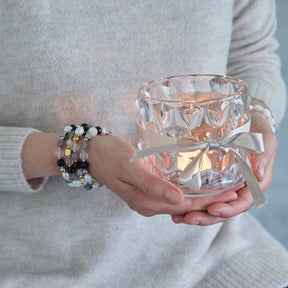 Frau trägt Armband HOPE gold/grau an Handgelenk, hält Kristallglas