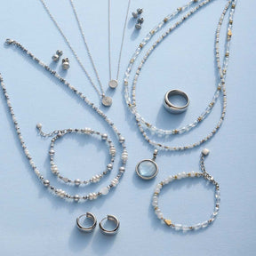 Schmuckkollektion mit Armbändern, Ketten, Ringen und Ohrringen aus Perlen und Metall auf hellem Hintergrund