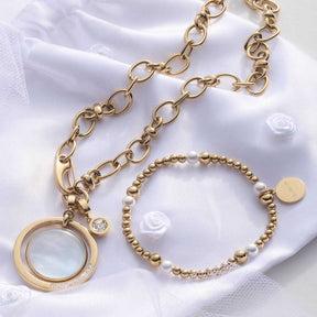 Halskette VIRGINIA gold mit Kettengliedern, Anhänger und Perlenarmband auf weißem Stoff