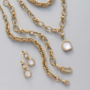 Creole VIRGINIA gold mit Perlmuttstein, passende Ohrringe und Ketten auf grauem Hintergrund