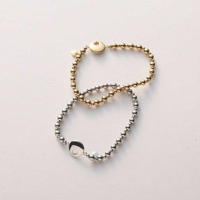 Armband SUE AMOUR aus silbernen und goldenen Perlen auf weißem Hintergrund
