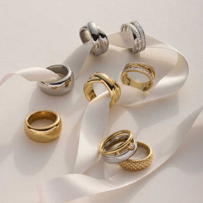 Mehrere Ringe in Gold- und Silbertönen auf weißem Seidenband arrangiert
